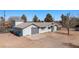 View of the single-story gray home with a metal roof, attached garage, and a spacious yard at 432 Bonelli Ave, Overton, NV 89040