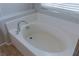 Close-up of white tiled soaking tub with chrome fixtures and window with blinds at 5596 Danforth Ave, Las Vegas, NV 89141