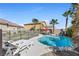 Inviting backyard swimming pool with lounge chairs, palm trees, rock features and a red umbrella in a serene setting at 746 Royal Course Ct, Las Vegas, NV 89148