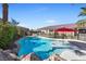 Sparkling swimming pool with rock accents, shallow tanning ledge, red umbrella, and landscaped backyard at 746 Royal Course Ct, Las Vegas, NV 89148