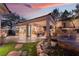 Outdoor living area with patio, seating, open doors to interior, and beautiful landscaping at dusk at 9825 Glenrock Dr, Las Vegas, NV 89134