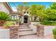 Elegant home entrance featuring stone pillars leading to a grand arched doorway and manicured greenery at 9825 Glenrock Dr, Las Vegas, NV 89134