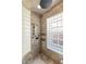 Close up on a glass block shower with travertine accents, shower head, and storage caddies at 9825 Glenrock Dr, Las Vegas, NV 89134