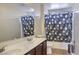 Functional bathroom showcasing a double sink vanity, tub with themed curtain, and tiled floors at 2865 Vigilante Ct, North Las Vegas, NV 89081