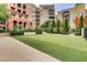 Building exterior displaying manicured lawn surrounded by trees and colorful architecture, offering a serene community view at 30 Strada Di Villaggio # 143, Henderson, NV 89011
