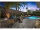 Backyard oasis with a sparkling pool, fire pit, outdoor kitchen, and lush tropical landscaping at 420 Pinnacle Heights Ln, Las Vegas, NV 89144