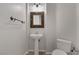 Clean and modern powder room featuring a pedestal sink, decorative mirror, and neutral tones at 420 Pinnacle Heights Ln, Las Vegas, NV 89144