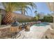 Outdoor living space with BBQ grill, seating area, and luxurious pool with waterfall feature at 420 Pinnacle Heights Ln, Las Vegas, NV 89144