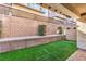 A charming backyard features low-maintenance turf and a retaining wall with shrubs for added privacy at 600 N Carriage Hill Dr # 1143, Las Vegas, NV 89138
