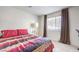 Cozy bedroom with a large window, carpet, and a red, purple, and white striped comforter at 6952 Midnight Bronze St, North Las Vegas, NV 89086