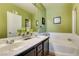 Well-lit bathroom showcasing a dual sink vanity, a tub, and tastefully decorated with light green paint at 7700 Constanso Ave # 204, Las Vegas, NV 89128