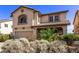 Two-story tan home with a tile roof, a two car garage and desert landscaping in the front yard at 774 Wigan Pier Dr, Henderson, NV 89002