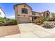 View of the front exterior of this tan home with a concrete driveway and desert landscaping at 774 Wigan Pier Dr, Henderson, NV 89002