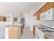 Kitchen with island, white appliances, wooden cabinets and view to living area at 774 Wigan Pier Dr, Henderson, NV 89002