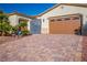 View of a home's two-car garage with decorative windows, paved driveway, and security gate at 8604 Amber Autumn St, Las Vegas, NV 89131