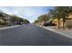 Street view showing the paved road, lined with houses and trees at 8824 Martin Downs Pl, Las Vegas, NV 89131