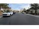 Neighborhood street with parked cars, homes and trees under a partly cloudy sky at 8824 Martin Downs Pl, Las Vegas, NV 89131