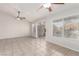 Bright living room featuring neutral tile flooring, ceiling fans, and a sliding glass door to the outside at 8920 Litchfield Ave, Las Vegas, NV 89134