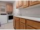 Well-lit laundry room featuring wood cabinets, washer, dryer, and tile flooring at 10709 Brinkwood Ave, Las Vegas, NV 89134