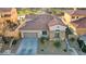 A high angle of a stucco single story home with tile roof, desert landscaping, and an attached two car garage at 1223 Casa Palermo Cir, Henderson, NV 89011