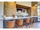 Beautiful bar area with stone accents, seating, and a selection of beverages at 1223 Casa Palermo Cir, Henderson, NV 89011