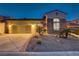 Charming home exterior featuring a two-car garage, stone accents, and desert landscaping at twilight at 1223 Casa Palermo Cir, Henderson, NV 89011