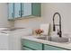 Close-up on a laundry room sink with teal cabinets, decor, and a modern, spring-neck faucet at 1223 Casa Palermo Cir, Henderson, NV 89011