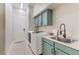 Well-lit laundry area with white washer and dryer, accented by teal cabinets and decor at 1223 Casa Palermo Cir, Henderson, NV 89011