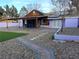 Charming backyard with covered patio, gravel landscaping, artificial turf, and a brick walkway at 18 Allegro St, Blue Diamond, NV 89004