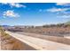 A desert landscape showing a concrete drainage ditch, homes, and hills under a bright blue, partially cloudy sky at 2633 Flare Star Dr, Henderson, NV 89044