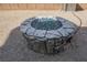 Close-up of a stone fire pit with clear glass, adding a cozy and stylish feature to the outdoor space at 2721 Benton Cove St, Laughlin, NV 89029