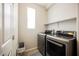 Modern laundry room with front loading washer and dryer, floating shelves and a window for natural light at 2721 Benton Cove St, Laughlin, NV 89029