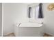 Bright bathroom showcasing a white soaking tub under a window with gray curtains and a decorative hat on the wall at 3430 Flagstone Ct # 2, Pahrump, NV 89048