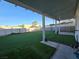 Backyard with green turf and covered patio including view of perimeter fence and exterior trees at 3550 Leor Ct, Las Vegas, NV 89121