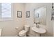 Neutral powder room with a pedestal sink, framed artwork, and white window shutters at 4775 E Beacon Ridge Dr, Pahrump, NV 89061