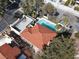 Aerial view showing a house with a pool, outdoor space, and a red tile roof surrounded by lush greenery at 5102 Tennis Ct, Las Vegas, NV 89120