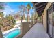 View of a balcony with decorative wall and tile-lined pool surrounded by trees and blue sky at 5102 Tennis Ct, Las Vegas, NV 89120