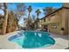 Backyard features a beautiful pool, patio, and a two-story home with desert landscaping at 5102 Tennis Ct, Las Vegas, NV 89120