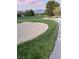 Scenic view of the lush golf course with a sand trap, showcasing manicured greens and a concrete cart path at 5980 E Drosetta Ave, Pahrump, NV 89061