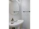 Bright half bathroom includes a modern pedestal sink, round mirror, and sleek black towel rack at 608 Breezy Sage Ct, Henderson, NV 89015