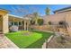 Backyard with artificial grass, brick-lined walkway, retaining wall, and desert landscaping at 668 Look Lively Ct, Henderson, NV 89011