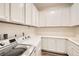 Bright laundry room featuring white cabinets, countertops, wood floors, and modern washer and dryer at 668 Look Lively Ct, Henderson, NV 89011