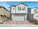 Two-story home featuring a two-car garage, gray stucco, and a paved driveway with desert landscaping at 6988 Sylmar Ave, Las Vegas, NV 89113