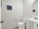 Modern half bathroom with a pedestal sink, toilet, and elegant wall decor at 6988 Sylmar Ave, Las Vegas, NV 89113