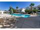 Community pool area featuring lounge chairs, tables, umbrellas, and palm trees creating a relaxing resort-like atmosphere at 7100 Pirates Cove Rd # 2067, Las Vegas, NV 89145