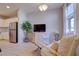 Bright living area showcasing wood-look tile floors, TV on cabinet, and a comfortable chair and ottoman at 720 Sleeping City Ave, Henderson, NV 89015