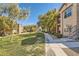 Exterior view of condo complex with grass area and walkways with many trees at 8000 W Badura Ave # 1019, Las Vegas, NV 89113