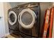 Modern front load gray washer and dryer with chrome accents and orange ladder in background at 8262 Huxley St, Las Vegas, NV 89123