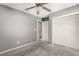 Carpeted bedroom with grey walls, a ceiling fan, walk-in closet and ensuite door at 8699 Grand Sequoia St, Las Vegas, NV 89139