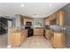 Well-lit kitchen with tiled floors, wooden cabinets, black appliances, and granite countertops at 8699 Grand Sequoia St, Las Vegas, NV 89139